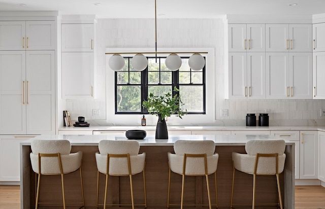 kitchen with a kitchen island, a breakfast bar area, white cabinetry, and light hardwood / wood-style floors