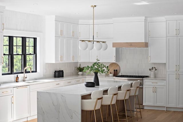 kitchen featuring light stone counters, a center island, white cabinets, sink, and a breakfast bar area