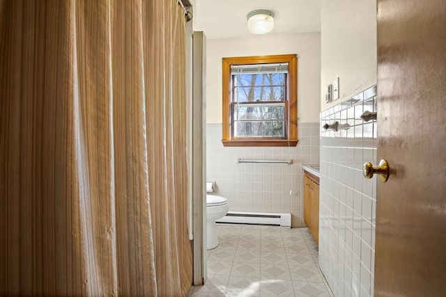 bathroom featuring a wainscoted wall, toilet, vanity, tile walls, and a baseboard radiator