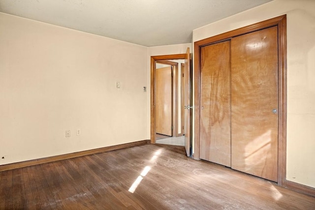 unfurnished bedroom featuring a closet, baseboards, and wood finished floors