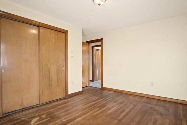 unfurnished bedroom featuring wood finished floors, a closet, and baseboards