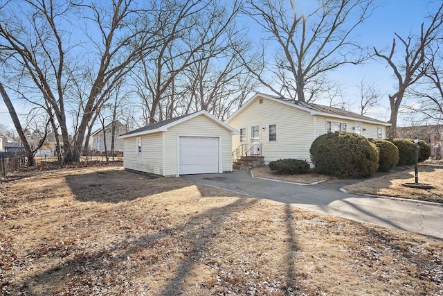 view of property exterior featuring an outbuilding, fence, a garage, and driveway