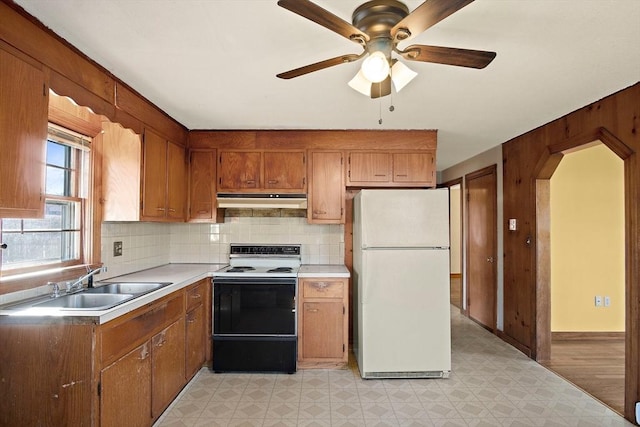 kitchen with range with electric cooktop, under cabinet range hood, light floors, freestanding refrigerator, and a sink