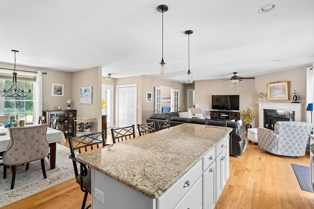 53 Gilbert Rd, Southampton, MA 01073 - kitchen featuring light wood-type flooring, white cabinets, pendant lighting, a ceiling fan, and light stone counters