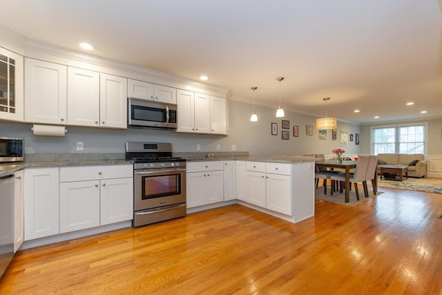 kitchen featuring stainless steel appliances, a peninsula, light wood finished floors, white cabinetry, and open floor plan