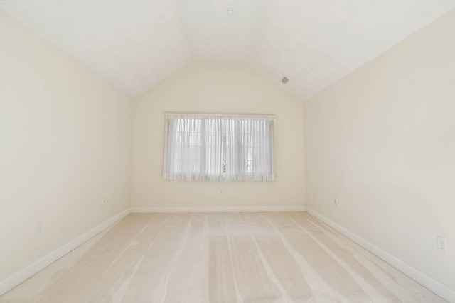 carpeted spare room with vaulted ceiling