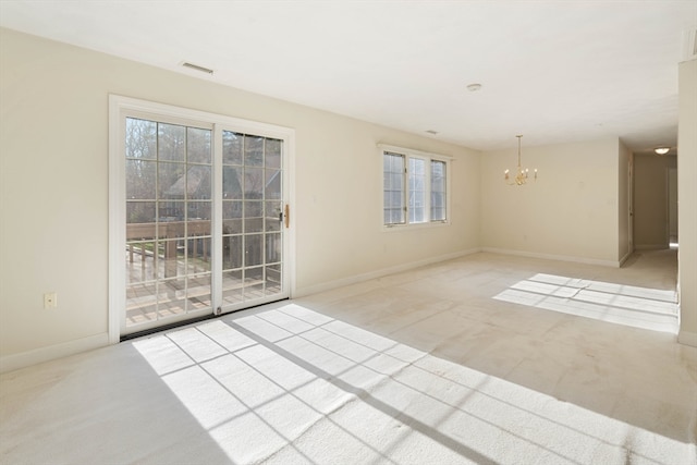 unfurnished room with light carpet, plenty of natural light, and an inviting chandelier