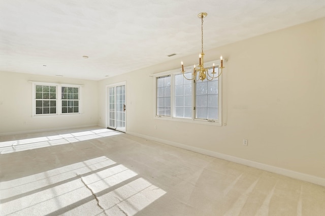 empty room featuring light carpet and a notable chandelier