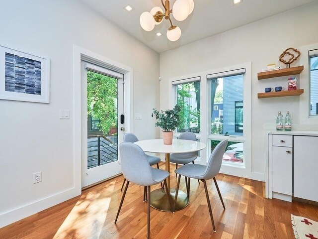 dining area with baseboards, an inviting chandelier, and light wood-style floors