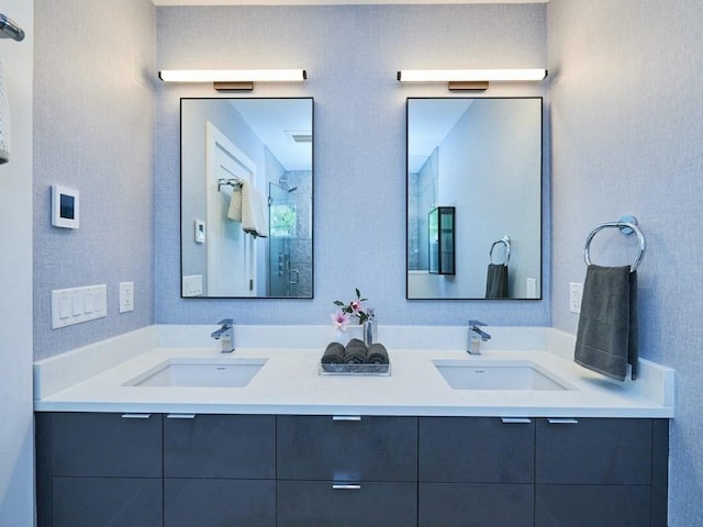 full bath featuring a shower with door, a sink, and double vanity