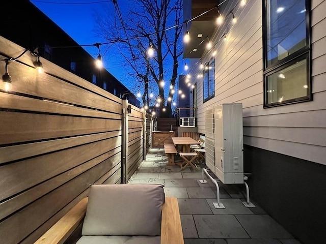 property exterior at night with a patio, outdoor dining area, and a fenced backyard