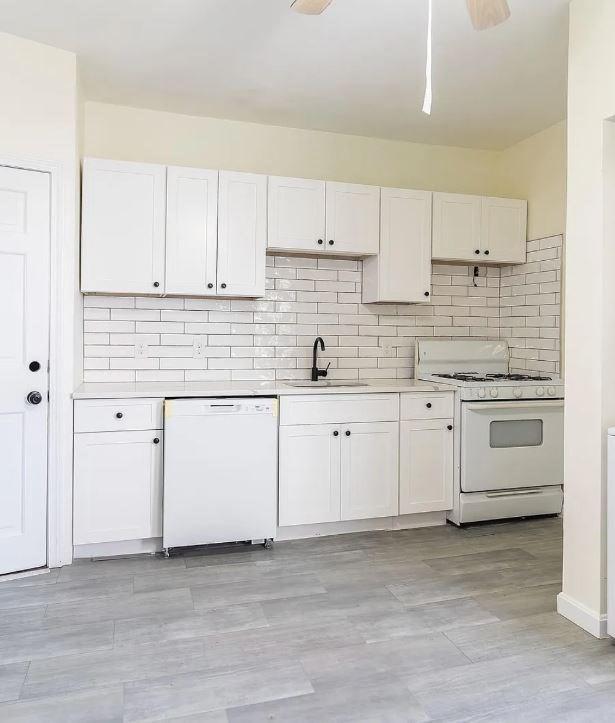 kitchen with white cabinetry, white appliances, and sink