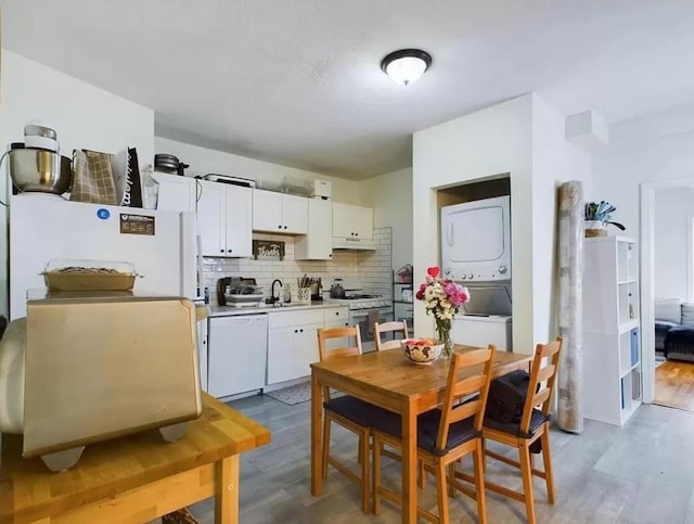 kitchen with stainless steel gas range oven, wood-type flooring, stacked washer and clothes dryer, dishwasher, and white cabinetry