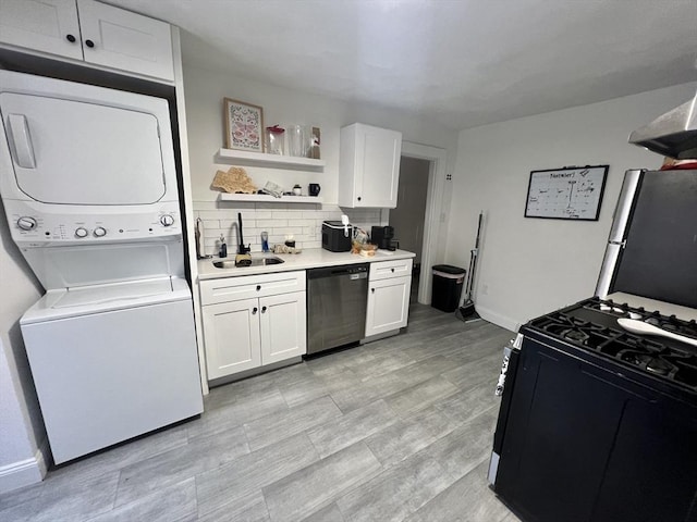 kitchen featuring white cabinetry, sink, stainless steel appliances, and stacked washer / drying machine