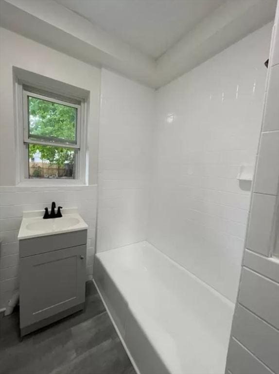 bathroom featuring a shower, vanity, and tile walls