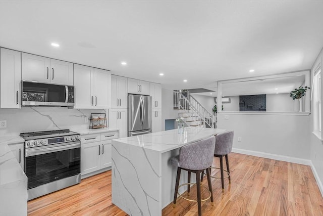 46 Curtis St, Brockton, MA 02301 - kitchen with stainless steel appliances, light stone countertops, a kitchen bar, a center island, and light wood-style floors