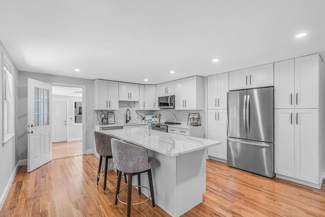46 Curtis St, Brockton, MA 02301 - kitchen featuring stainless steel appliances, light stone counters, light wood finished floors, a breakfast bar area, and recessed lighting