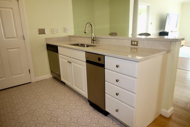 kitchen featuring white cabinetry, sink, stainless steel dishwasher, kitchen peninsula, and light hardwood / wood-style floors