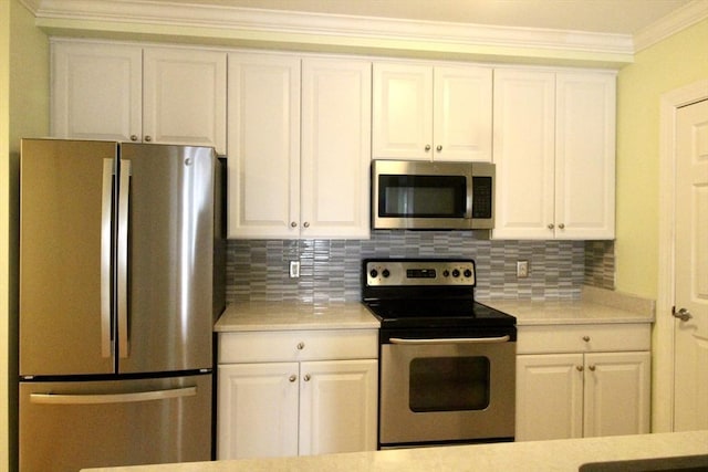 kitchen featuring tasteful backsplash, white cabinets, stainless steel appliances, and ornamental molding