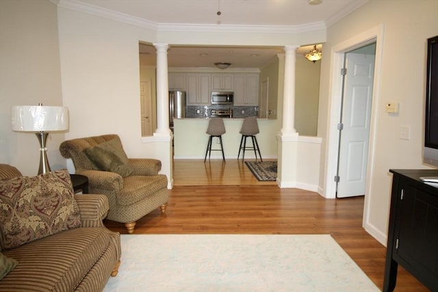 living room with hardwood / wood-style flooring, ornate columns, and crown molding