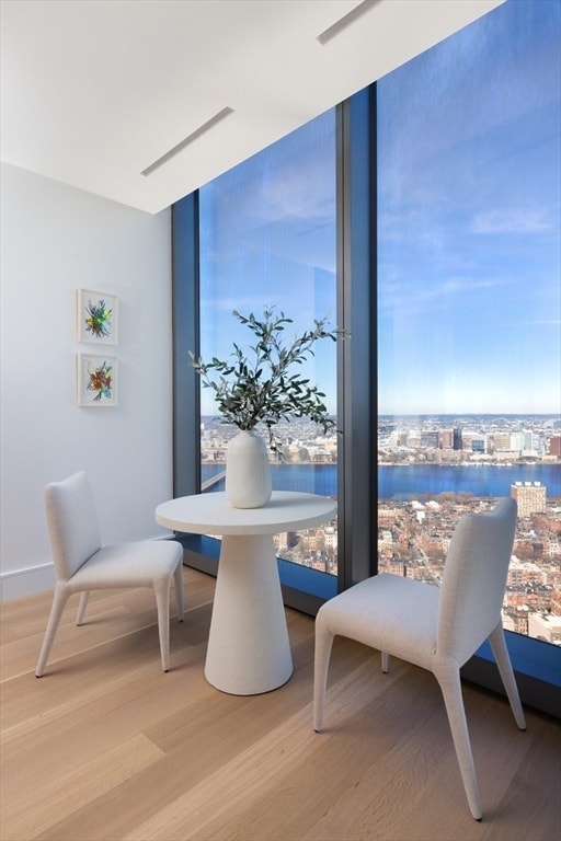 dining area with a water view, light wood-type flooring, and expansive windows