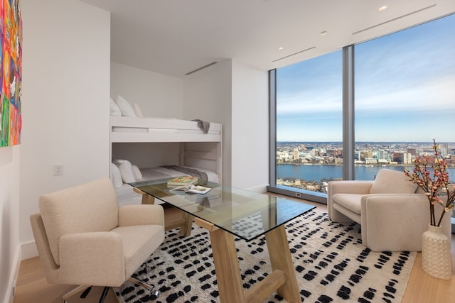 living room featuring light hardwood / wood-style flooring, a water view, and a wall of windows