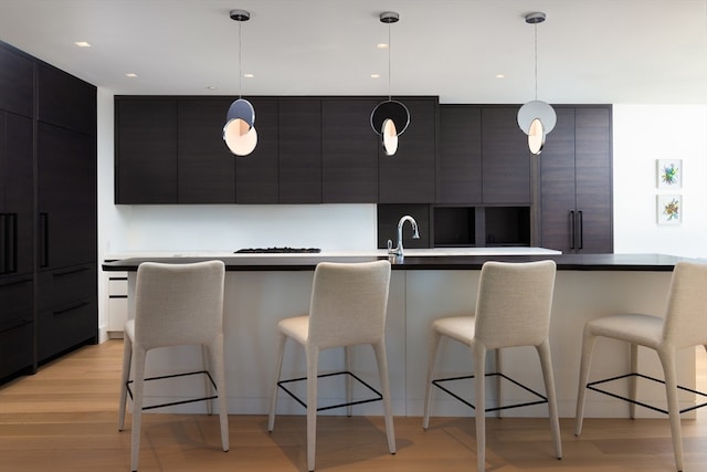 kitchen with hanging light fixtures, light hardwood / wood-style flooring, and a breakfast bar