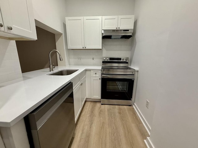 kitchen featuring appliances with stainless steel finishes, light countertops, under cabinet range hood, white cabinetry, and a sink