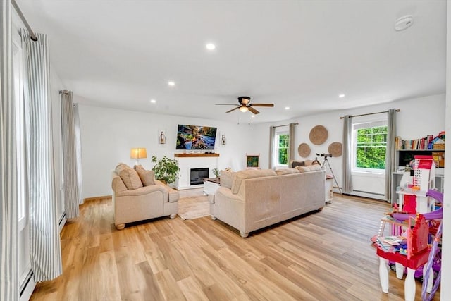182 Sheldon Rd, Fitchburg, MA 01420 - living room featuring light wood-style floors, a ceiling fan, recessed lighting, a glass covered fireplace, and a baseboard heating unit