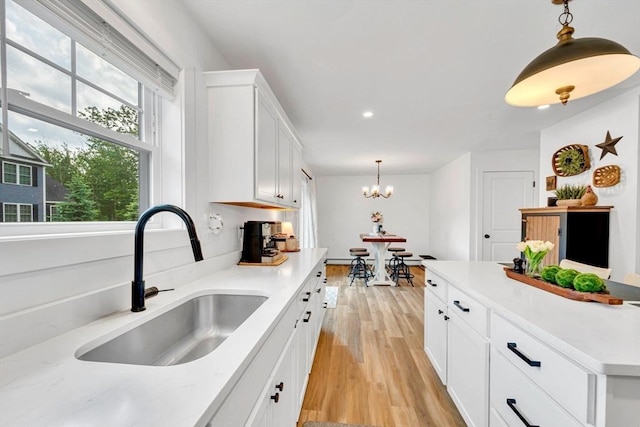 182 Sheldon Rd, Fitchburg, MA 01420 - kitchen featuring light wood-type flooring, white cabinetry, decorative light fixtures, light countertops, and a chandelier