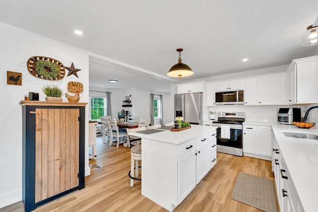 182 Sheldon Rd, Fitchburg, MA 01420 - kitchen featuring appliances with stainless steel finishes, white cabinets, a center island, light countertops, and a breakfast bar area
