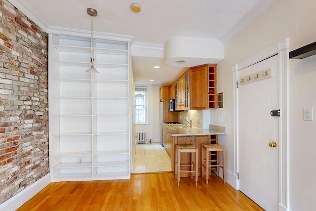 11 Irving St Unit 4, Boston, MA 02114 - kitchen featuring open shelves, brown cabinetry, brick wall, light wood-style floors, and radiator heating unit