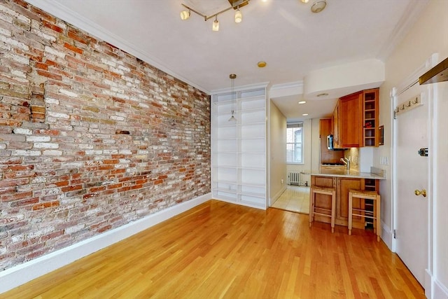 11 Irving St Unit 4, Boston, MA 02114 - unfurnished dining area with brick wall, light wood-style flooring, radiator heating unit, ornamental molding, and baseboards