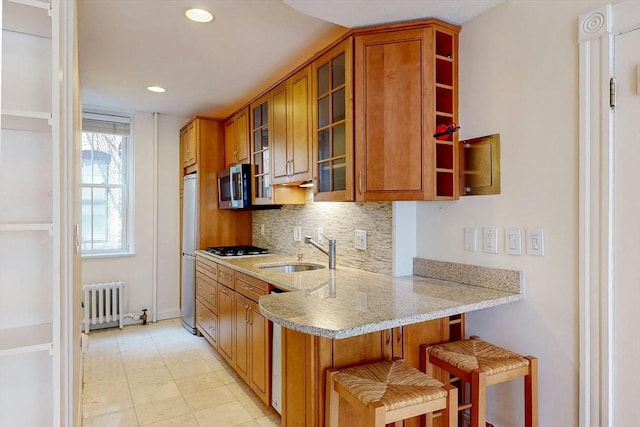 11 Irving St Unit 4, Boston, MA 02114 - kitchen with radiator heating unit, a sink, brown cabinetry, stainless steel microwave, and refrigerator
