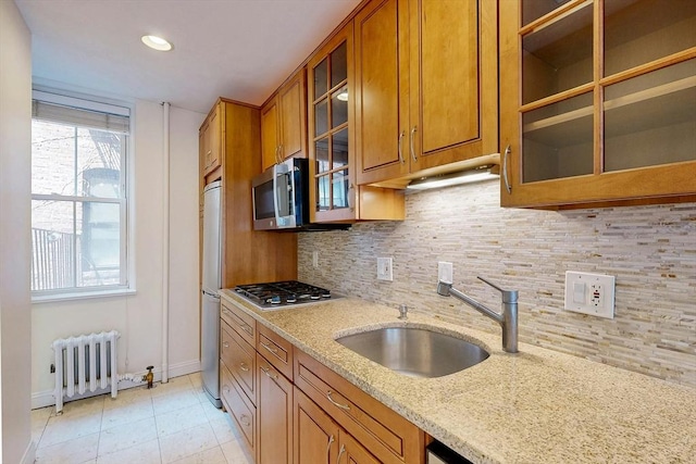 11 Irving St Unit 4, Boston, MA 02114 - kitchen with radiator heating unit, brown cabinetry, a sink, and recessed lighting