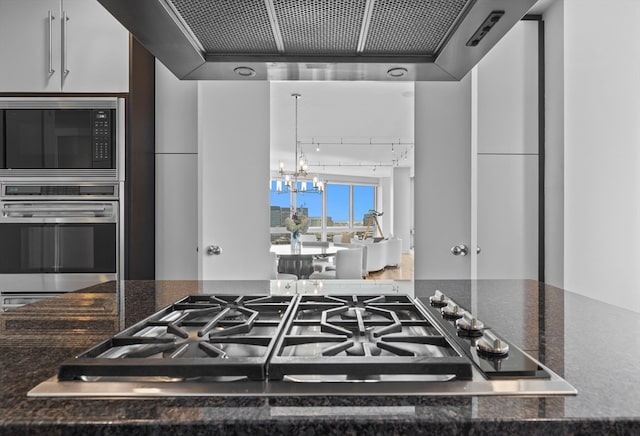 kitchen with stainless steel gas cooktop, ventilation hood, and a chandelier