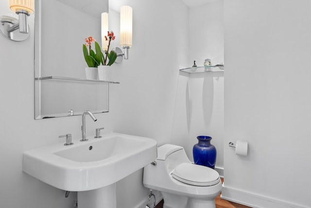 bathroom featuring toilet, wood-type flooring, and sink