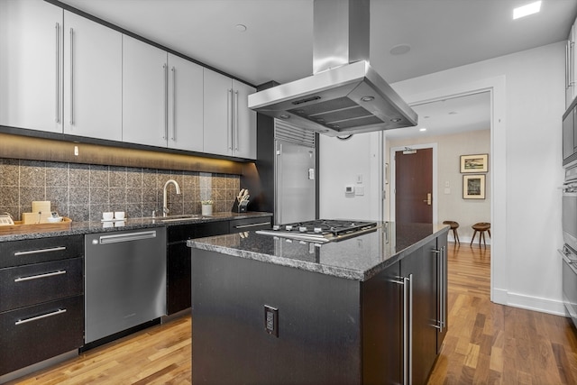 kitchen featuring a kitchen island, island exhaust hood, stainless steel appliances, light wood-type flooring, and white cabinets