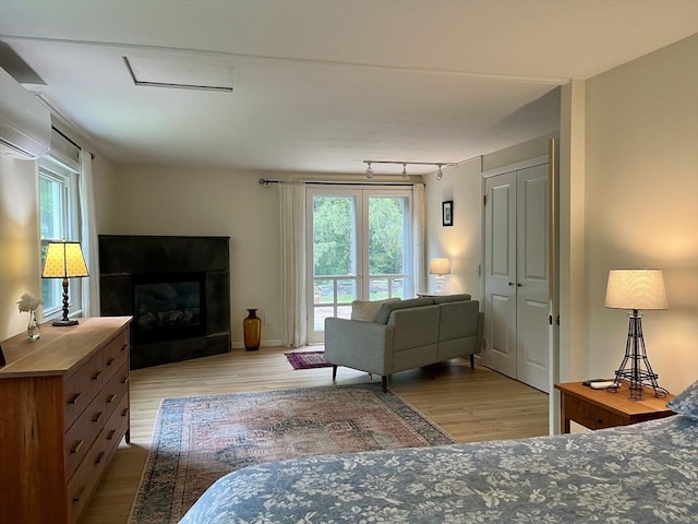 947 Burts Pit Rd, Northampton, MA 01062 - bedroom featuring wood finished floors, multiple windows, a wall mounted air conditioner, and a glass covered fireplace