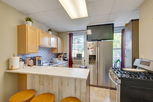 kitchen with kitchen peninsula, stainless steel fridge with ice dispenser, a kitchen breakfast bar, gas stove, and a wealth of natural light