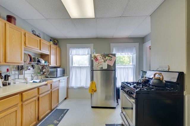 kitchen featuring light brown cabinets, appliances with stainless steel finishes, and a paneled ceiling