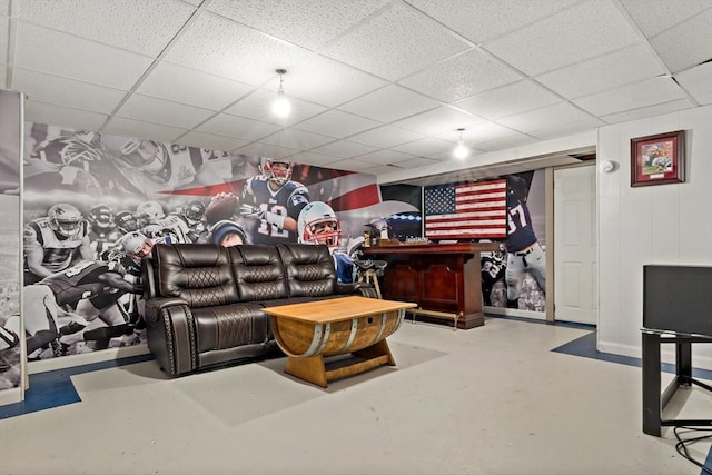 living room with a drop ceiling, concrete floors, and bar