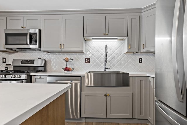 kitchen featuring gray cabinets, tasteful backsplash, appliances with stainless steel finishes, and sink