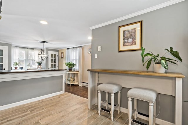 kitchen featuring hanging light fixtures, crown molding, a wealth of natural light, and light hardwood / wood-style floors