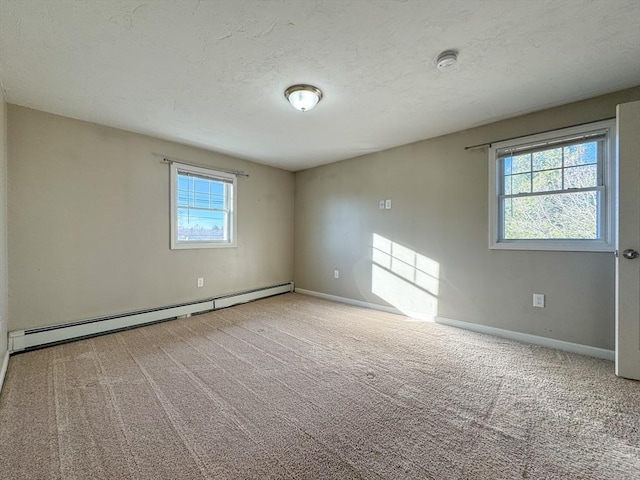 empty room featuring carpet floors, a healthy amount of sunlight, and a baseboard heating unit