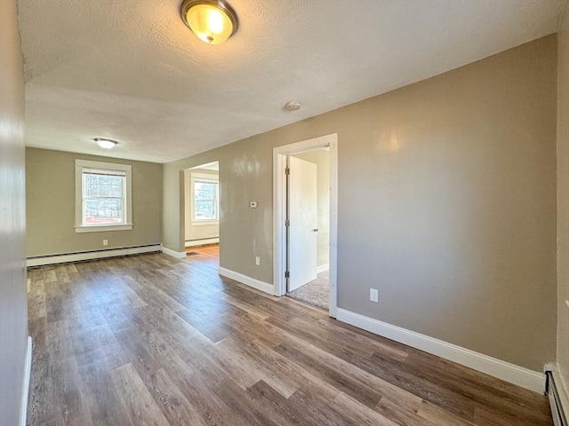 spare room featuring hardwood / wood-style flooring, a baseboard radiator, and a textured ceiling