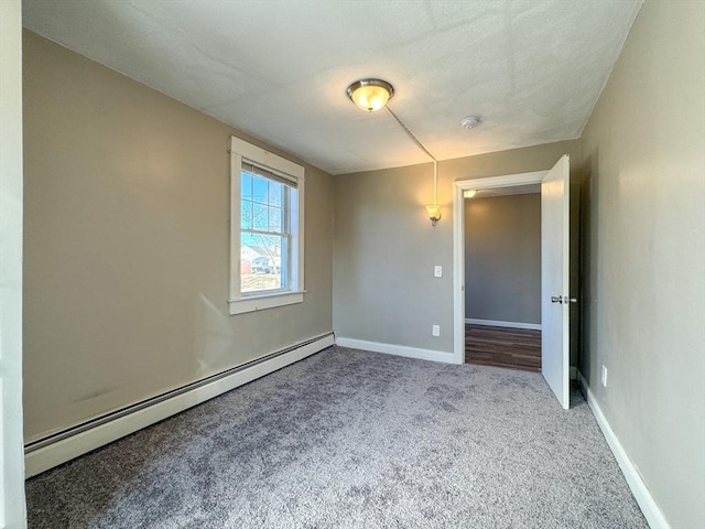 spare room featuring a baseboard heating unit and carpet