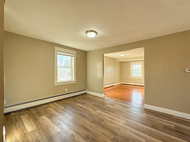 empty room featuring baseboard heating and a healthy amount of sunlight