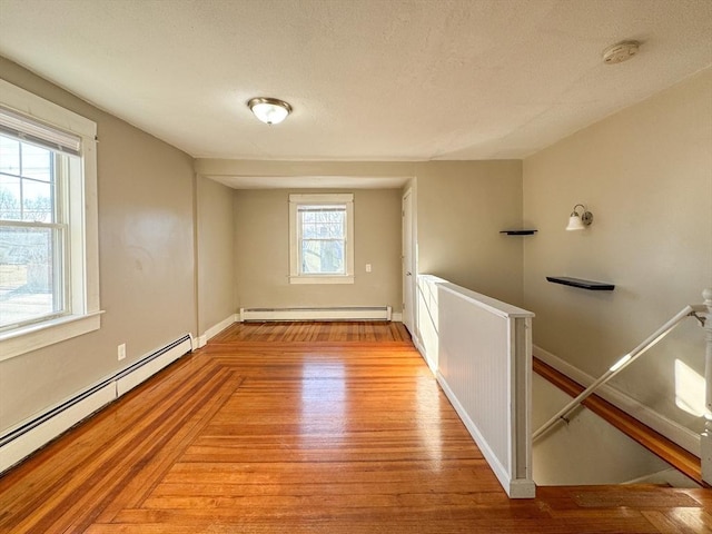 empty room featuring a baseboard heating unit and light hardwood / wood-style flooring