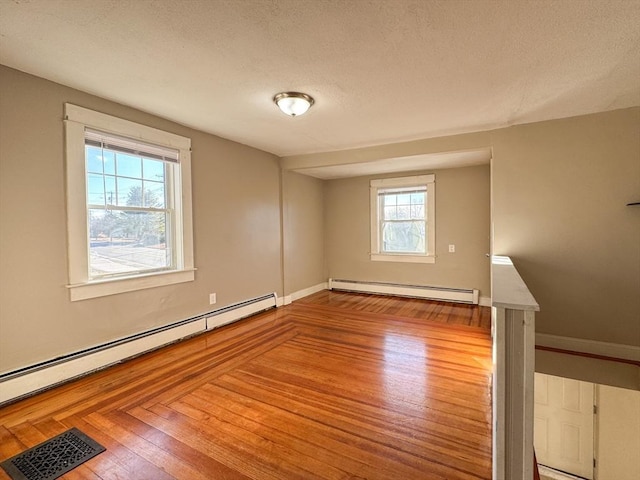 spare room featuring plenty of natural light, hardwood / wood-style floors, and baseboard heating